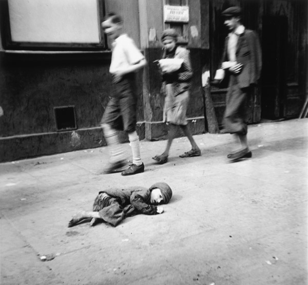 Ein hilfloses Kind liegt auf dem Pflaster im Warschauer Ghetto, Jungen gehen vorbei ...
